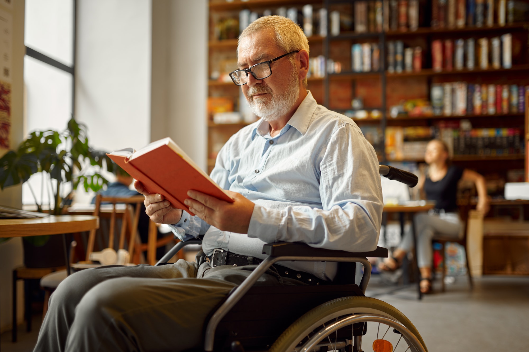 Adult disabled man in wheelchair reading a book